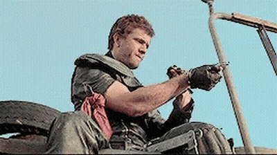 A Man Sitting In A Vehicle With A Gun In His Hand GIF