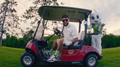 A Man Sitting In A Yamaha Golf Cart Next To A Stuffed Rabbit GIF