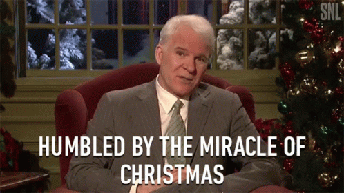 A Man Sitting In Front Of A Christmas Tree With The Words Humbled By The Miracle Of Christmas GIF