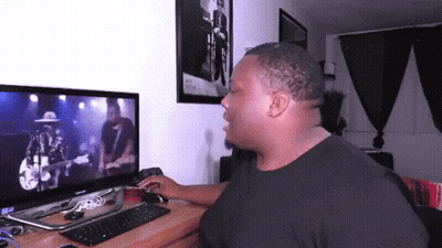 A Man Sitting In Front Of A Computer Monitor Watching A Video GIF