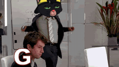 A Man Sitting In Front Of A Computer With A Cat Mascot Behind Him With The Letter G In The Foreground GIF