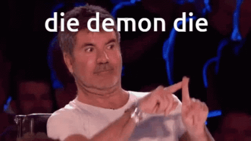 A Man Sitting In Front Of A Crowd With The Words Die Demon Die On His Face GIF
