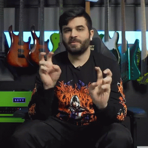 A Man Sitting In Front Of A Green Revv Amplifier GIF