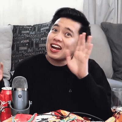 A Man Sitting In Front Of A Microphone In Front Of A Pillow That Says Milan On It GIF
