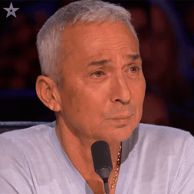 A Man Sitting In Front Of A Microphone With A Star In The Upper Right Corner GIF