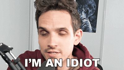 A Man Sitting In Front Of A Microphone With His Eyes Closed And The Words I 'M An Idiot Below Him GIF