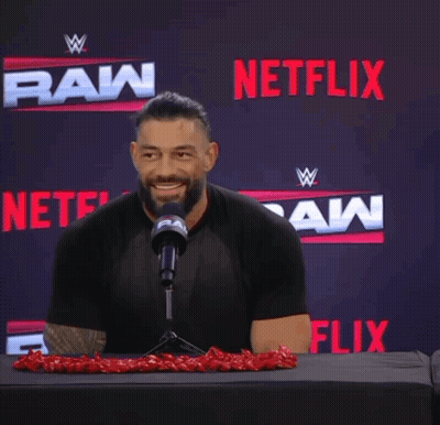 A Man Sitting In Front Of A Microphone With Netflix In The Background GIF