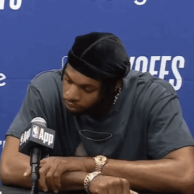 A Man Sitting In Front Of A Microphone With The Nba App Logo On It GIF