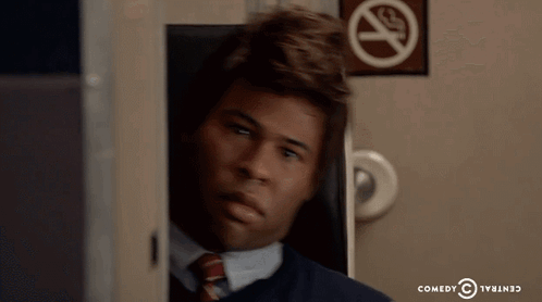 A Man Sitting In Front Of A No Smoking Sign From Comedy Central GIF