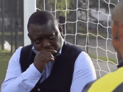 A Man Sitting In Front Of A Soccer Net With His Hand To His Chin GIF