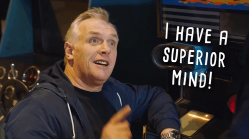 A Man Sitting In Front Of An Arcade Machine With The Words " I Have A Superior Mind " Above Him GIF