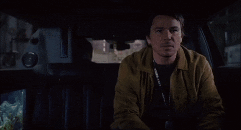 A Man Sitting In The Back Seat Of A Car With A Lanyard Around His Neck That Says ' Fortune ' On It GIF