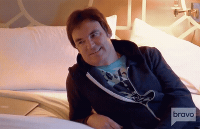 A Man Sitting On A Bed With Bravo Written On The Bottom Right GIF