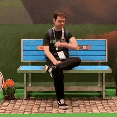 A Man Sitting On A Blue Bench Wearing A Black Shirt That Says Feel Lucky GIF