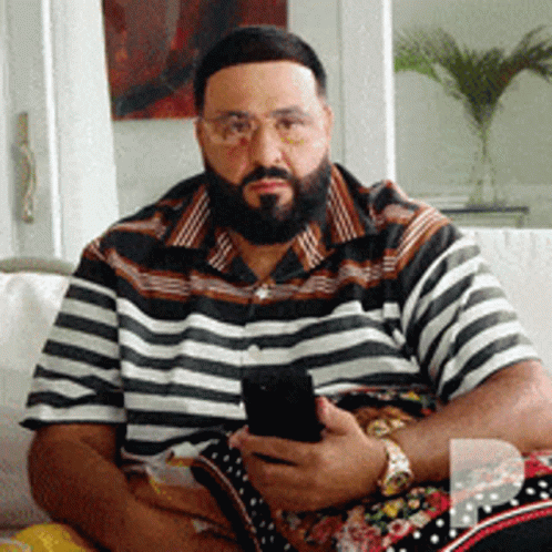 A Man Sitting On A Couch Holding A Cell Phone GIF