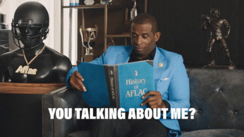 A Man Sitting On A Couch Reading A Book Titled History Of Aflg GIF