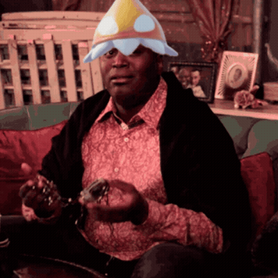 A Man Sitting On A Couch Wearing A Flower Hat GIF