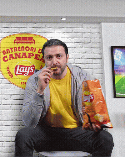 A Man Sitting On A Couch With A Bag Of Lays Chips GIF