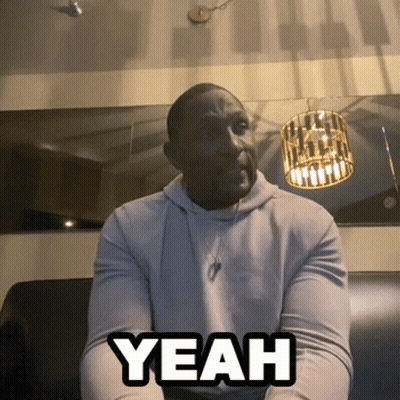 A Man Sitting On A Couch With The Word Yeah Written On His Chest GIF