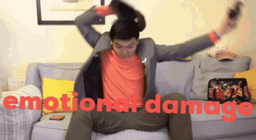 A Man Sitting On A Couch With The Words Emotional Damage Written On The Bottom GIF