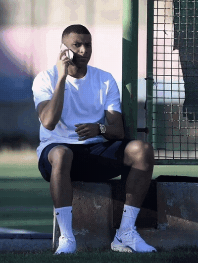 A Man Sitting On A Ledge Talking On A Cellphone GIF