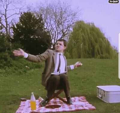 A Man Sitting On A Picnic Blanket With His Arms Outstretched GIF