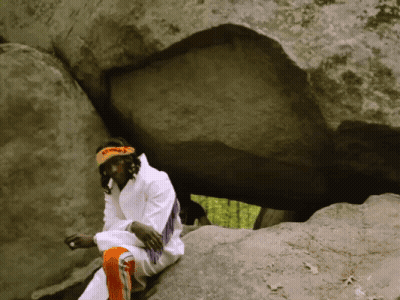 A Man Sitting On A Rock With A Headband That Says ' I Am A Native American ' On It GIF