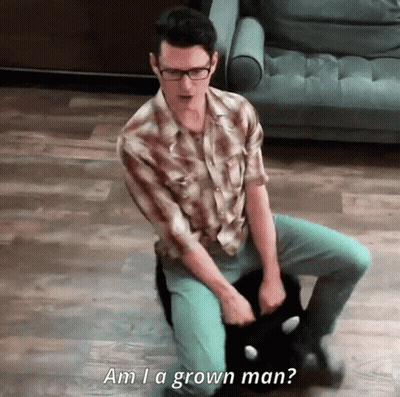 A Man Sitting On The Floor Holding A Cat With The Words Am I A Grown Man Written Below Him GIF
