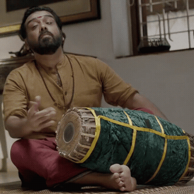 A Man Sitting On The Floor Playing A Drum GIF