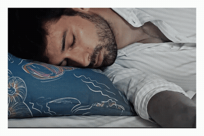 A Man Sleeping With His Head On A Blue Pillow With Seashells On It GIF