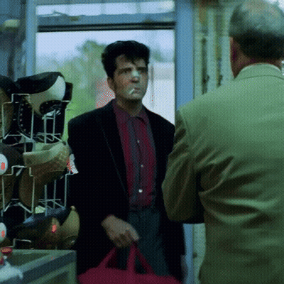 A Man Smoking A Cigarette And Holding A Red Bag GIF
