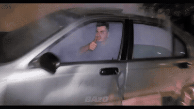 A Man Smoking A Cigarette In A Car With The Word Bazo On The Side GIF