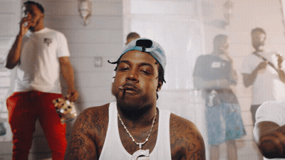 A Man Smoking A Cigarette In Front Of A Group Of Men GIF