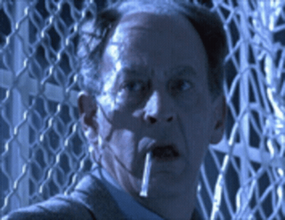 A Man Smoking A Cigarette In Front Of A Wire Fence GIF