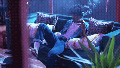 A Man Smoking A Cigarette While Laying On A Couch GIF