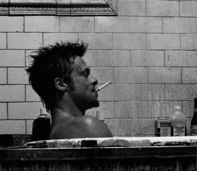 A Man Smoking A Cigarette While Taking A Bath In A Bathtub Surrounded By Bottles Of Medicine GIF