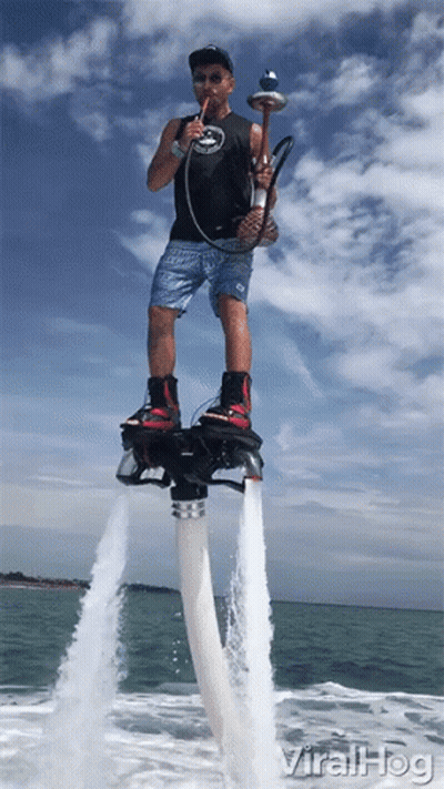 A Man Smoking A Hookah While Standing On A Water Jet Board GIF