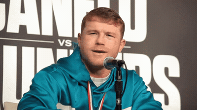 A Man Speaking Into A Microphone In Front Of A Sign That Says Juan U Vs Juniors GIF