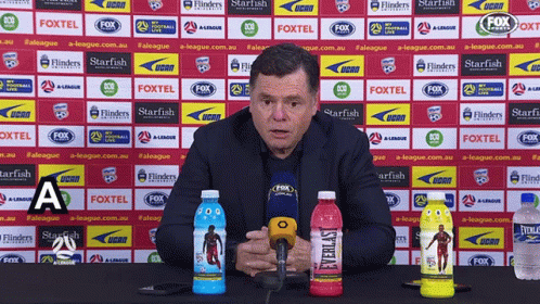 A Man Speaking Into A Microphone In Front Of A Wall With Fox Logos On It GIF