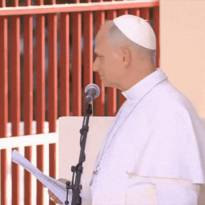 A Man Speaking Into A Microphone While Wearing A White Hat GIF