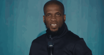 A Man Speaking Into A Microphone With His Mouth Open GIF
