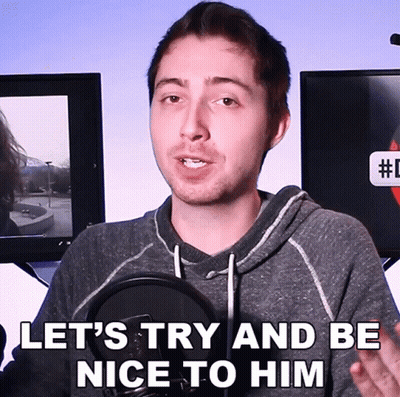 A Man Speaking Into A Microphone With The Words " Let 'S Try And Be Nice To Him " Above Him GIF