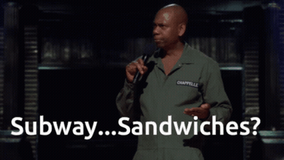 A Man Speaking Into A Microphone With The Words " Subway Sandwiches " Behind Him GIF