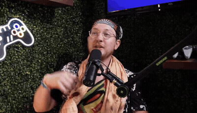 A Man Speaking Into A Shure Microphone In Front Of A Video Game Controller Sign GIF