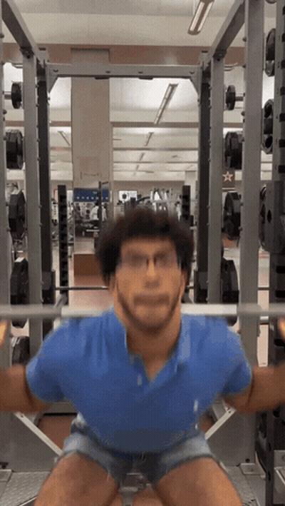 A Man Squatting With A Barbell In A Gym With A Star On The Wall GIF