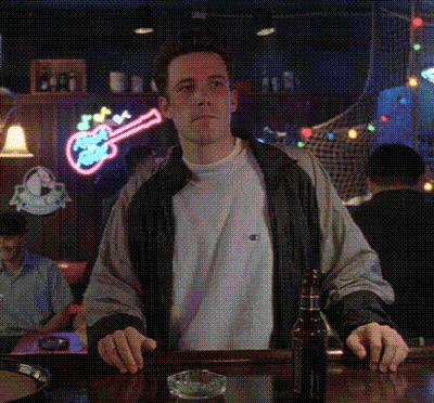 A Man Standing At A Bar With A Bottle Of Beer And A Guitar Neon Sign Behind Him GIF