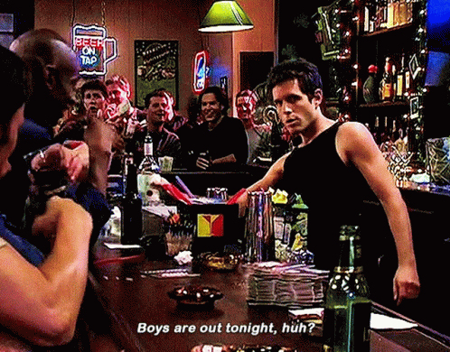 A Man Standing At A Bar With A Sign That Says Beer On Tap On It GIF