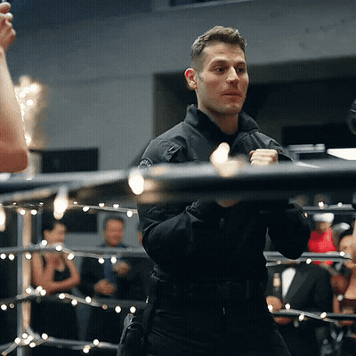 A Man Standing In A Boxing Ring With A Badge On His Chest GIF