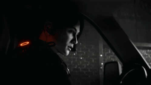 A Man Standing In A Dark Room With A Blue Light Shining On Him GIF