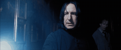 A Man Standing In A Dark Room With A Light Shining On Him GIF